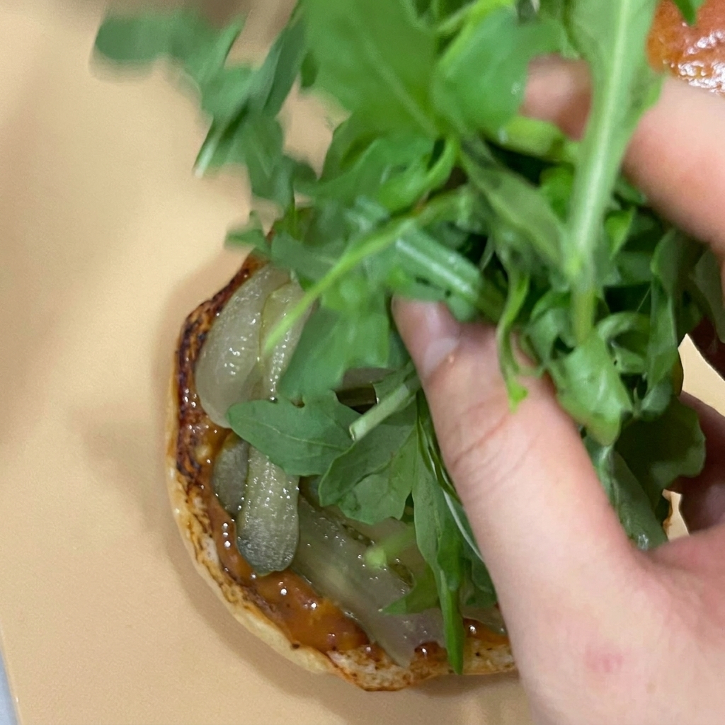 Eine Handvoll Rucola wird auf die Gurken gelegt.