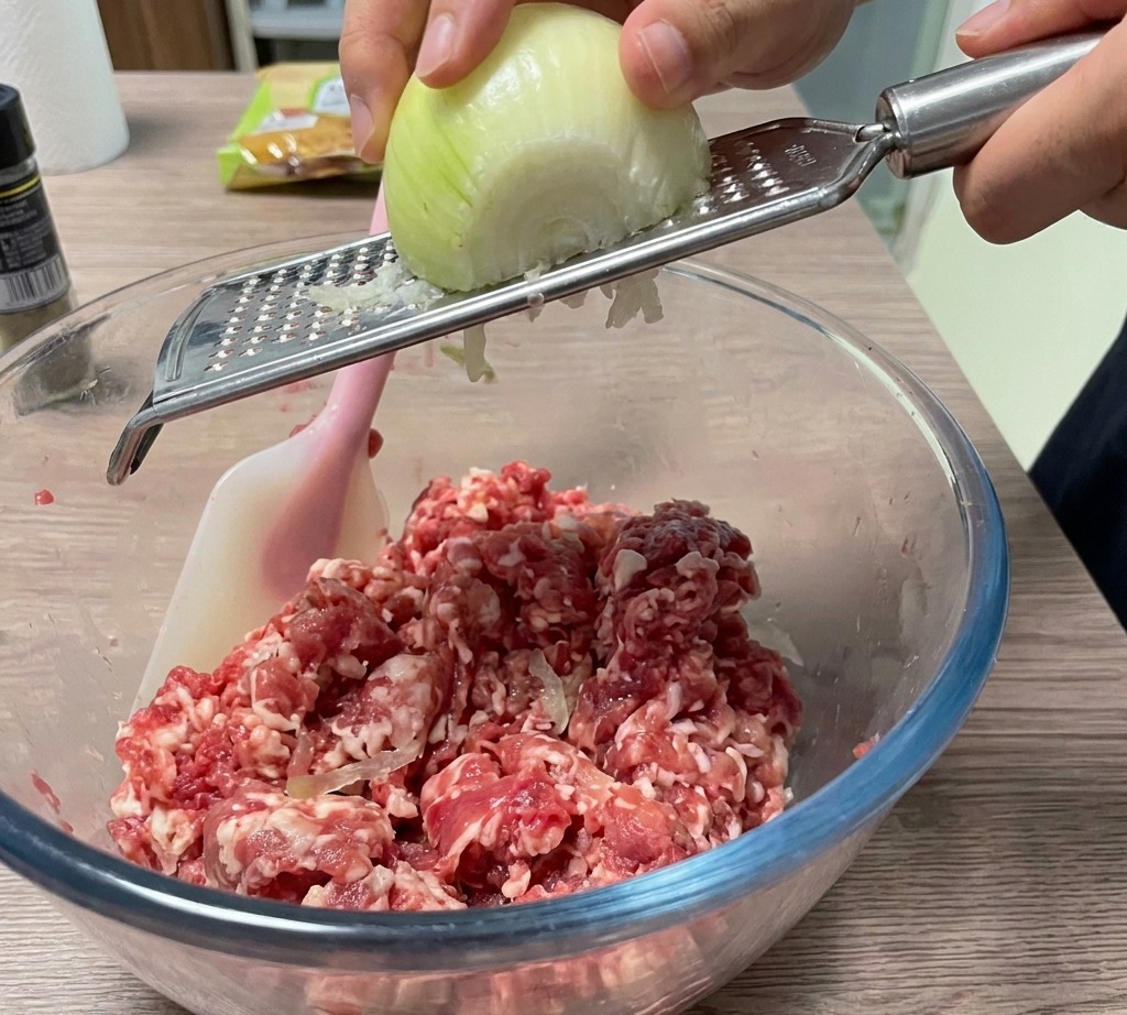 Eine Zwiebel wird direkt in die Fleischschüssel gerieben.