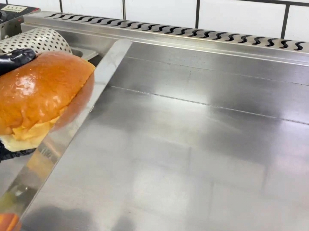 Halbierte Hamburger-Brötchen werden auf einer Grillplatte goldbraun getoastet.