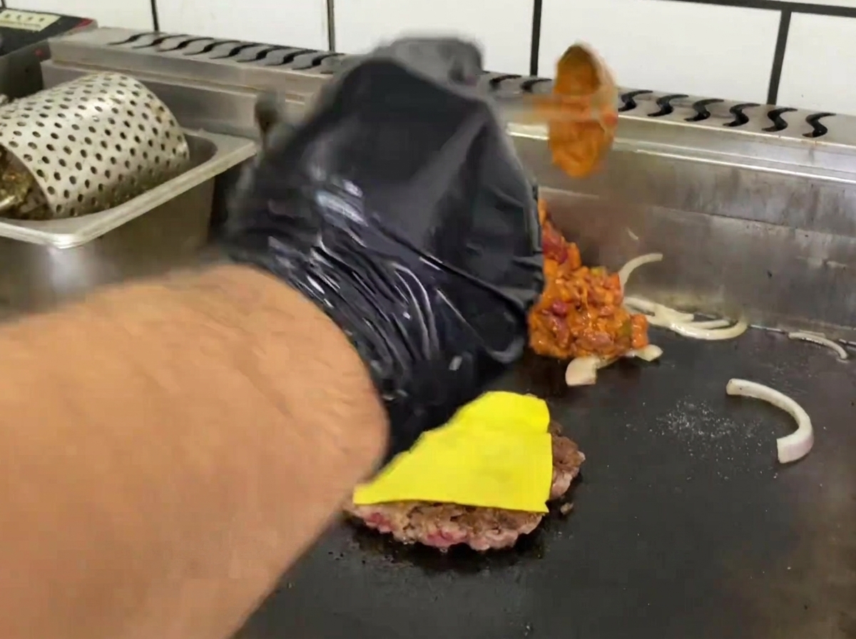 Mexikanische Chili-Sauce wird neben dem Patty auf der Grillplatte erhitzt.