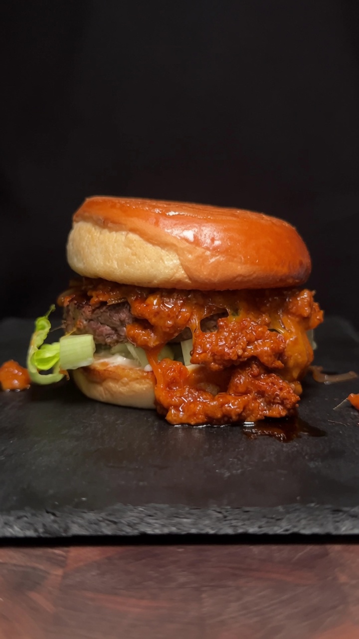 Ein Gourmet-Choriqueso-Burger mit einem dicken Rindfleisch-Patty und einer aromatischen Chorizo-Käse-Soße auf einem getoasteten Bun.