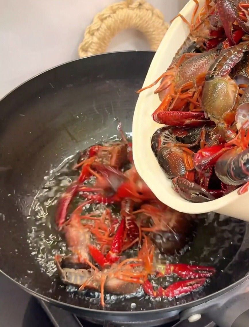 Flusskrebse werden zum Frittieren in einen heißen Wok mit Öl gegeben.