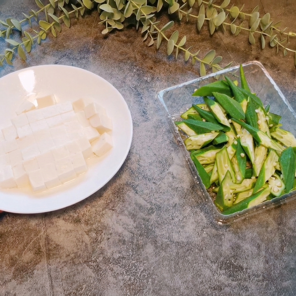 Ein Block Weichtofu wird auf einem weißen Teller in gleichmäßige kleine Würfel geschnitten.