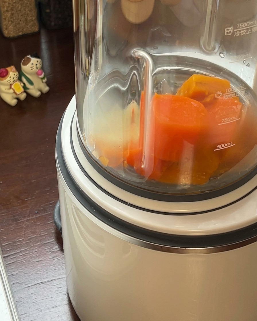 Gekochtes Kürbis-Gemüse-Gemisch wird in einen Standmixer gegeben.