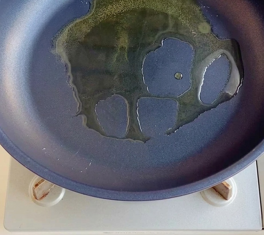 Gewürfelte rote Zwiebeln in einer Pfanne mit Öl.