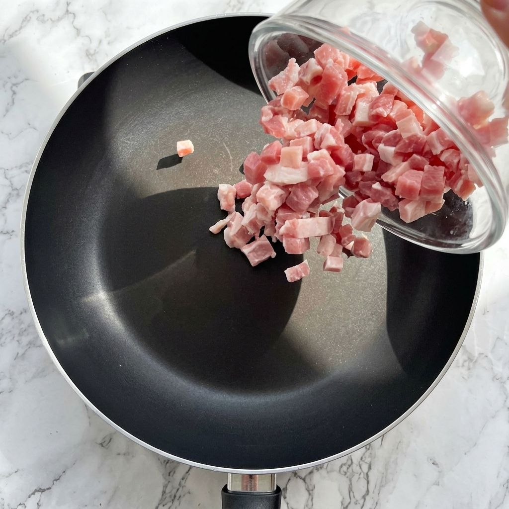 Gewürfelter Speck wird in einer Pfanne goldbraun angebraten.
