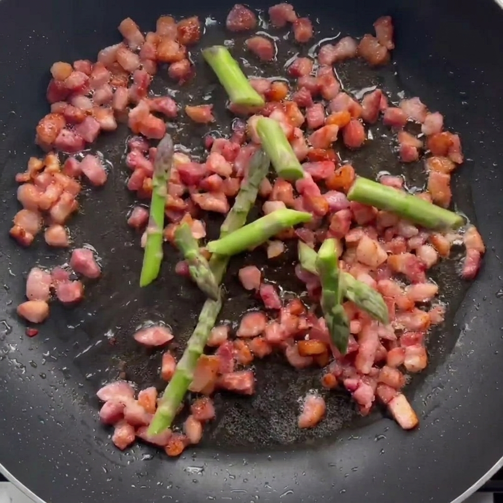Spargelstücke in der Pfanne mit den gebräunten Speckwürfeln.