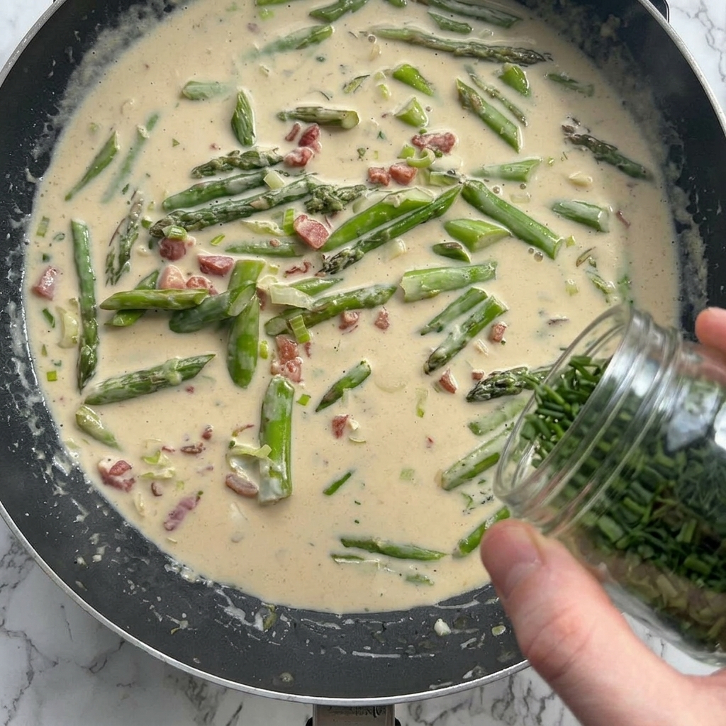 Parmesan und Kräuter werden in die cremige Sauce gestreut.