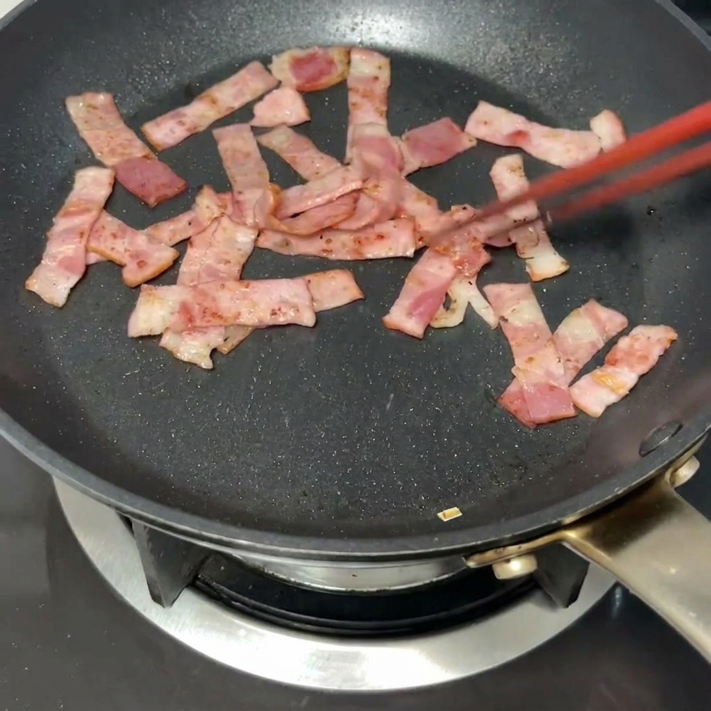 Ein Stück Butter schmilzt in der Pfanne zusammen mit den gebräunten Speckstücken.