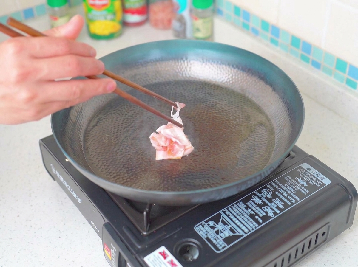 Goldbraune Speckstücke braten in einer Pfanne.
