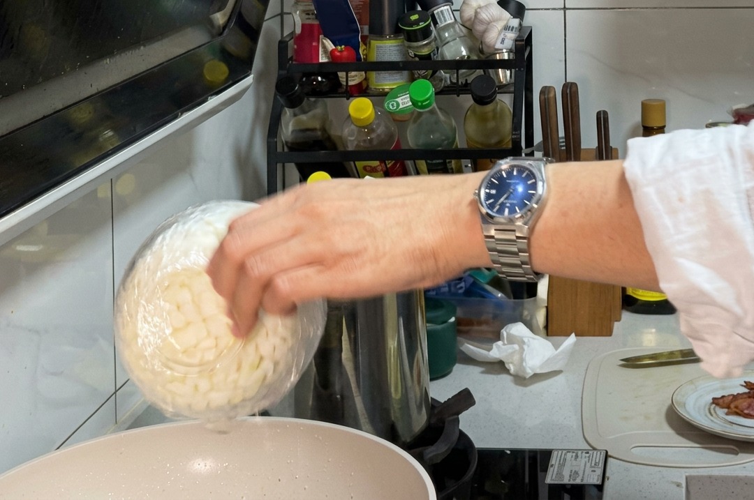 Gehackte Zwiebeln und Pilzscheiben garen zusammen im Speckfett in einer Pfanne.