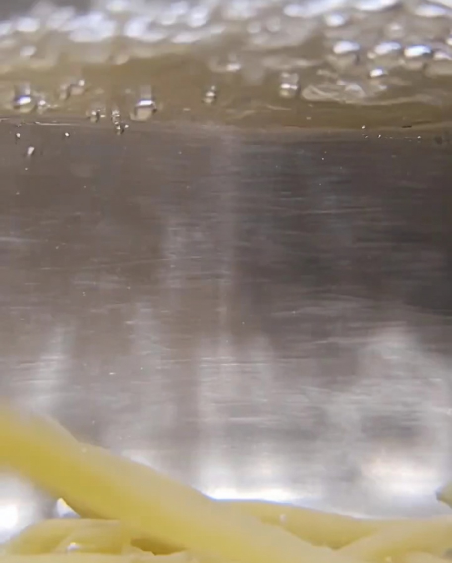Nahaufnahme von trockener, gedrehter Trofie-Pasta in sprudelnd kochendem Wasser.