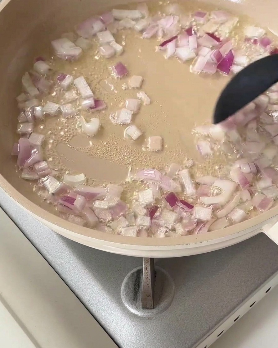 Rote Zwiebelwürfel brutzeln in einer Pfanne mit heißem Speiseöl.