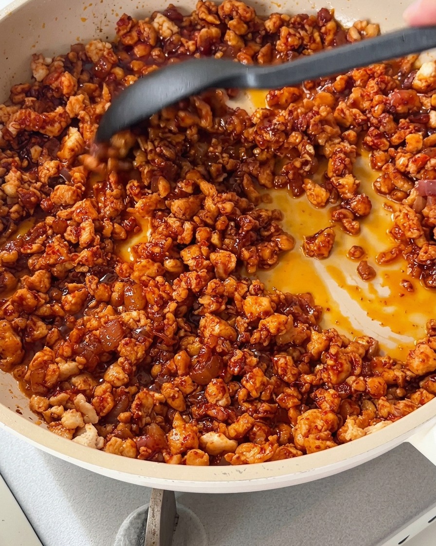 Hähnchenmischung mit bunter, gewürfelter Paprika in einer Pfanne.