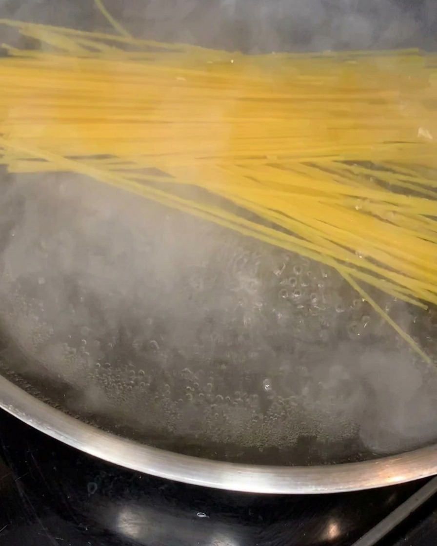 Spaghetti kochen in einem großen Topf mit sprudelndem Wasser.