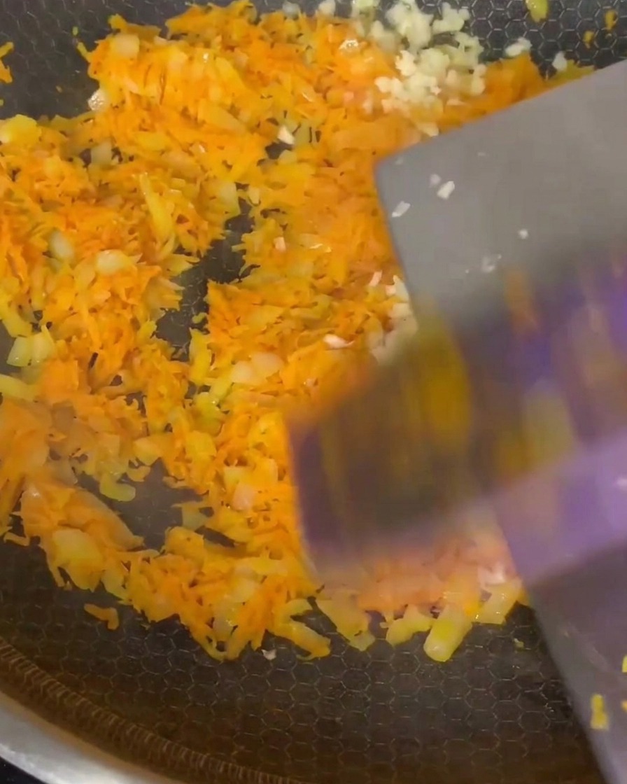 Gehackter Knoblauch und italienische Kräuter werden unter das gedünstete Gemüse gemischt.