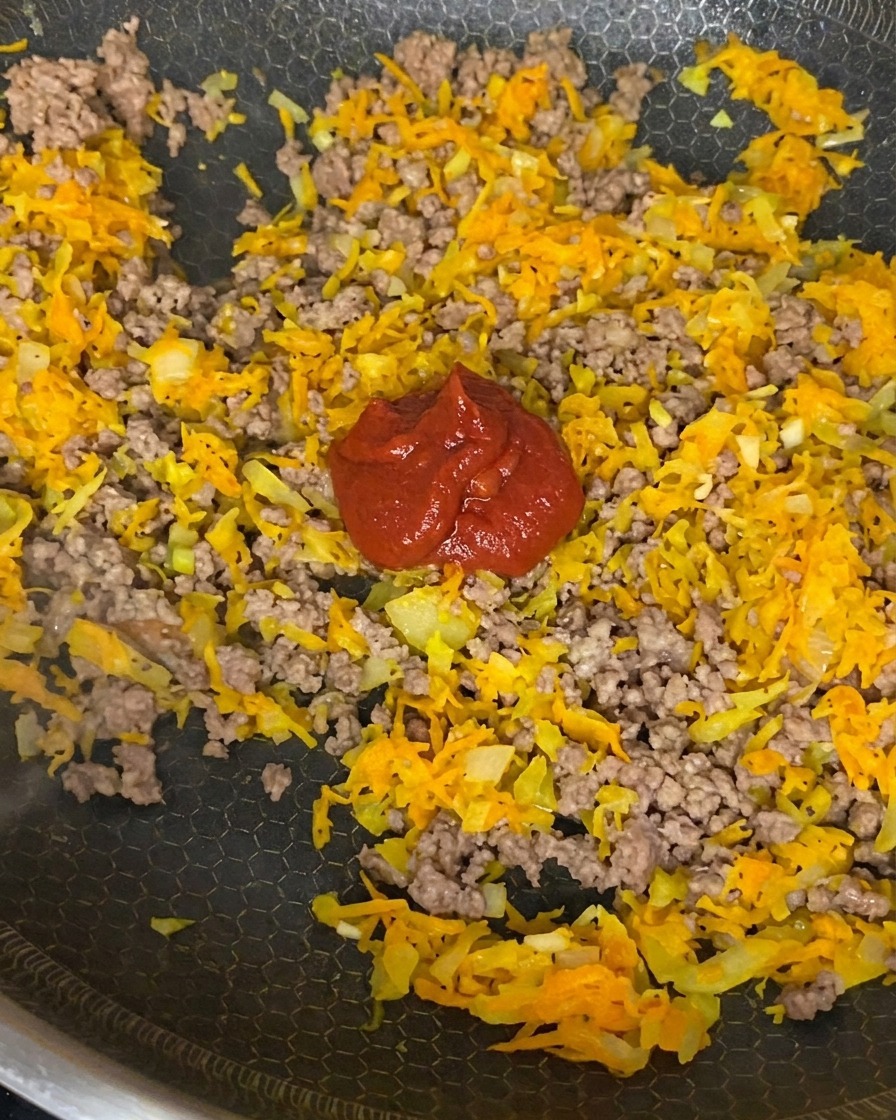 Tomatenmark, gestückelte Tomaten und Sojasauce werden unter das Fleisch-Gemüse-Gemisch gerührt.