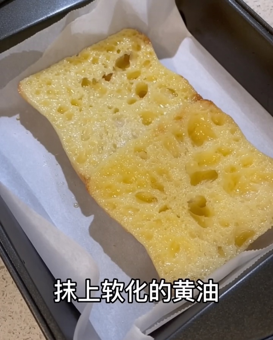 Zimmerwarme Butter wird auf die mit Knoblauch eingeriebene Ciabatta gestrichen.