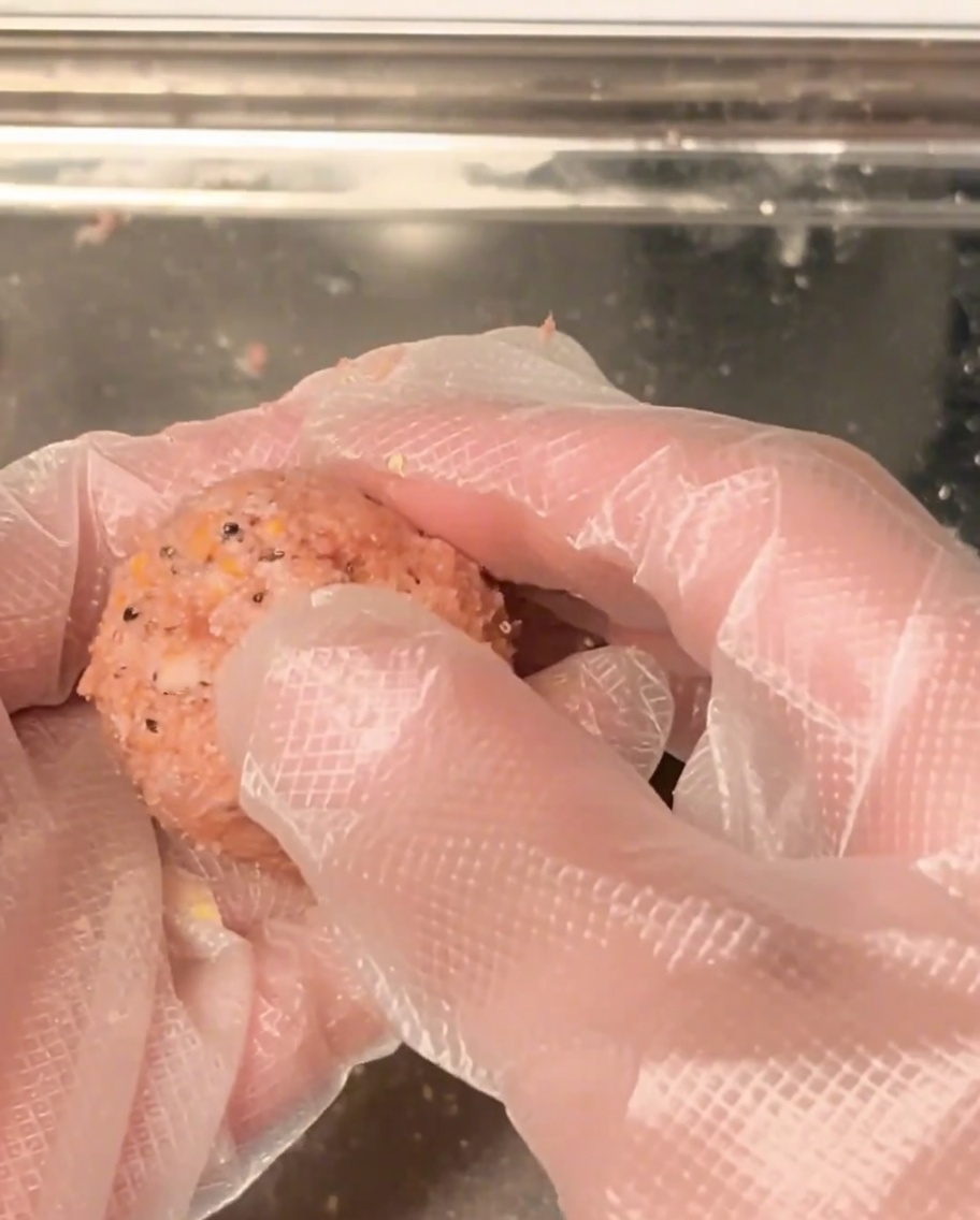 Hände rollen rohes Hackfleisch zu einer gleichmäßigen Kugel.