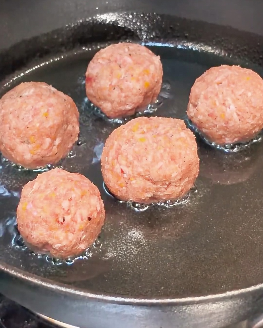 Rohe Hackbällchen braten in einer heißen Pfanne mit Öl.