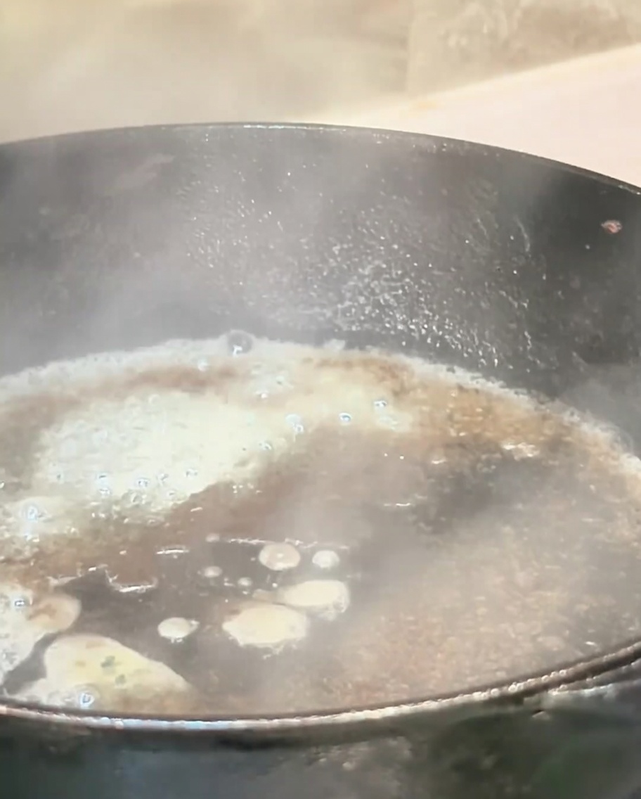 Kochende Flüssigkeit in einer heißen Pfanne setzt Dampf frei und löst den Bratensatz.