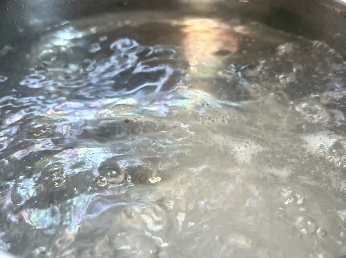 Trockene Spaghetti werden in einen großen Topf mit sprudelnd kochendem Wasser getaucht.
