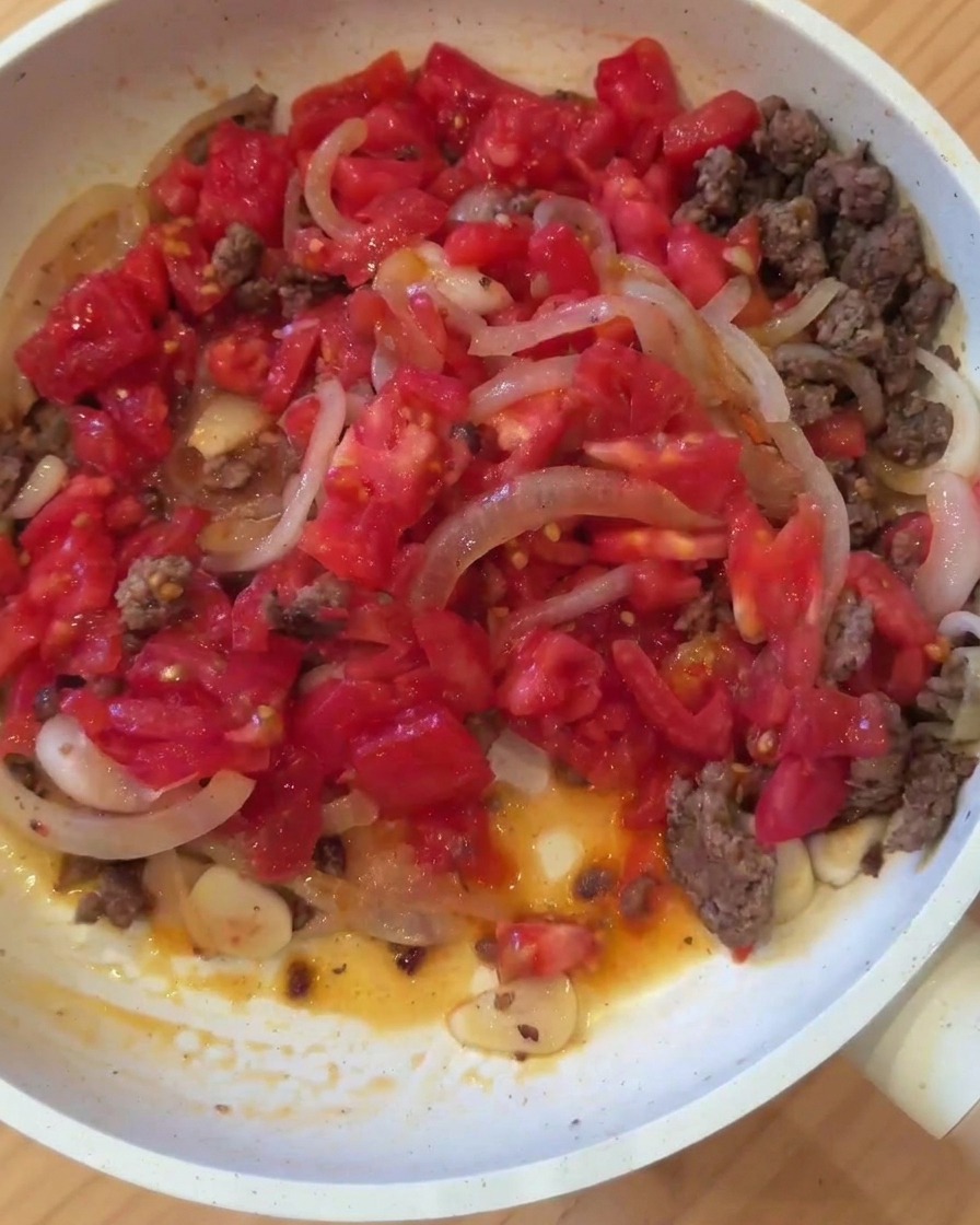 Die Zutaten für die Fleischsauce köcheln zusammen in einer Pfanne.