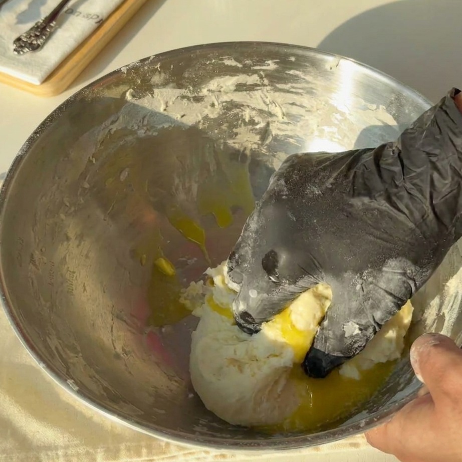 Goldene, geschmolzene Butter wird über den Teig in einer Metallschüssel gegossen.