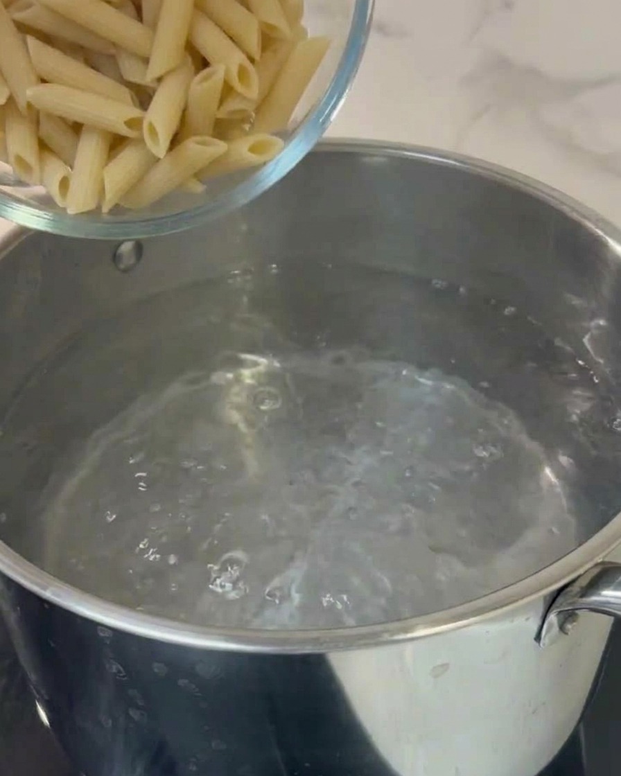 Penne werden in einen Topf mit kochendem Wasser gegeben.