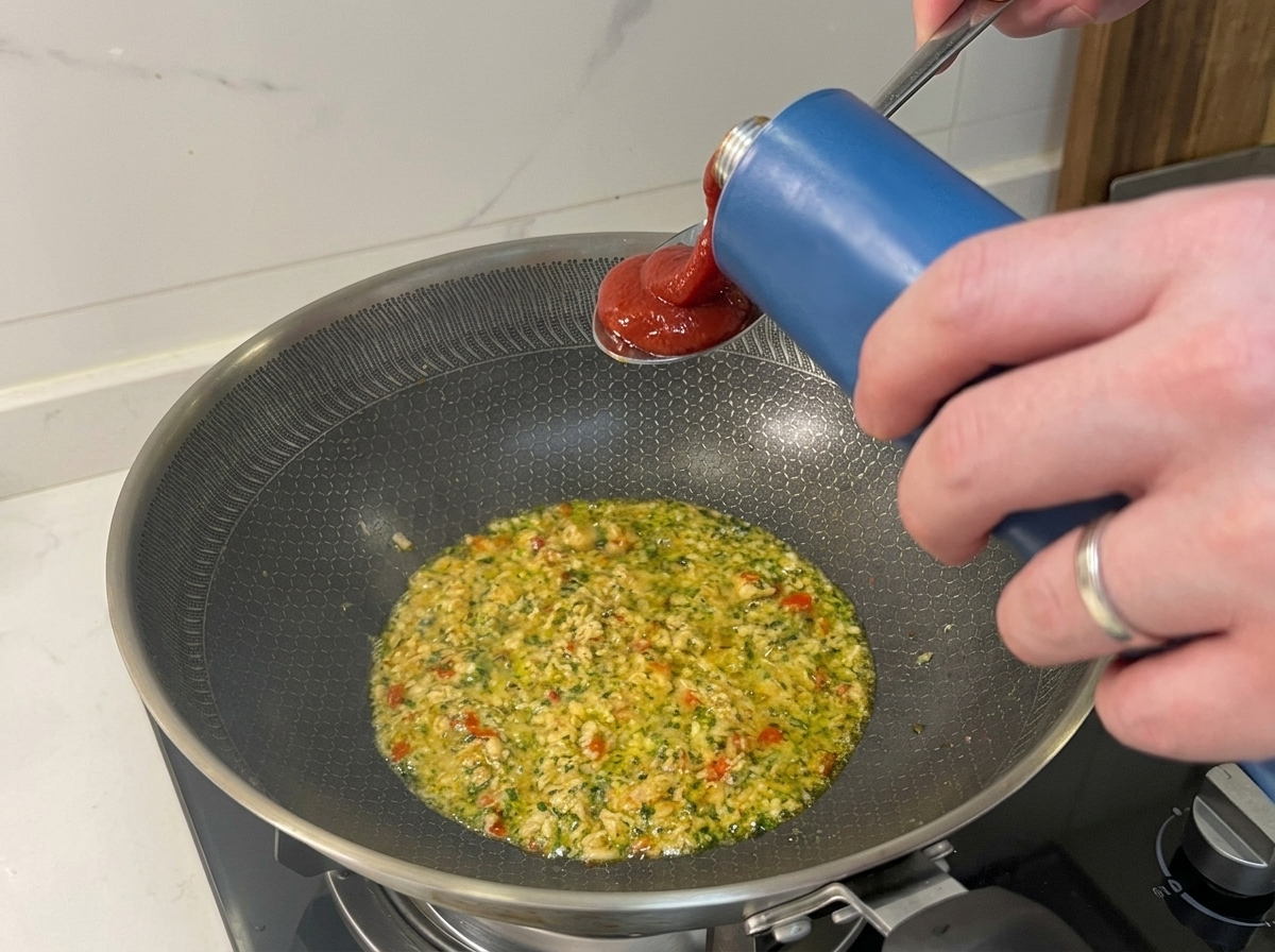 Passierte Tomaten werden in eine Pfanne mit dem angebratenen Thunfisch und den Aromaten gegossen.