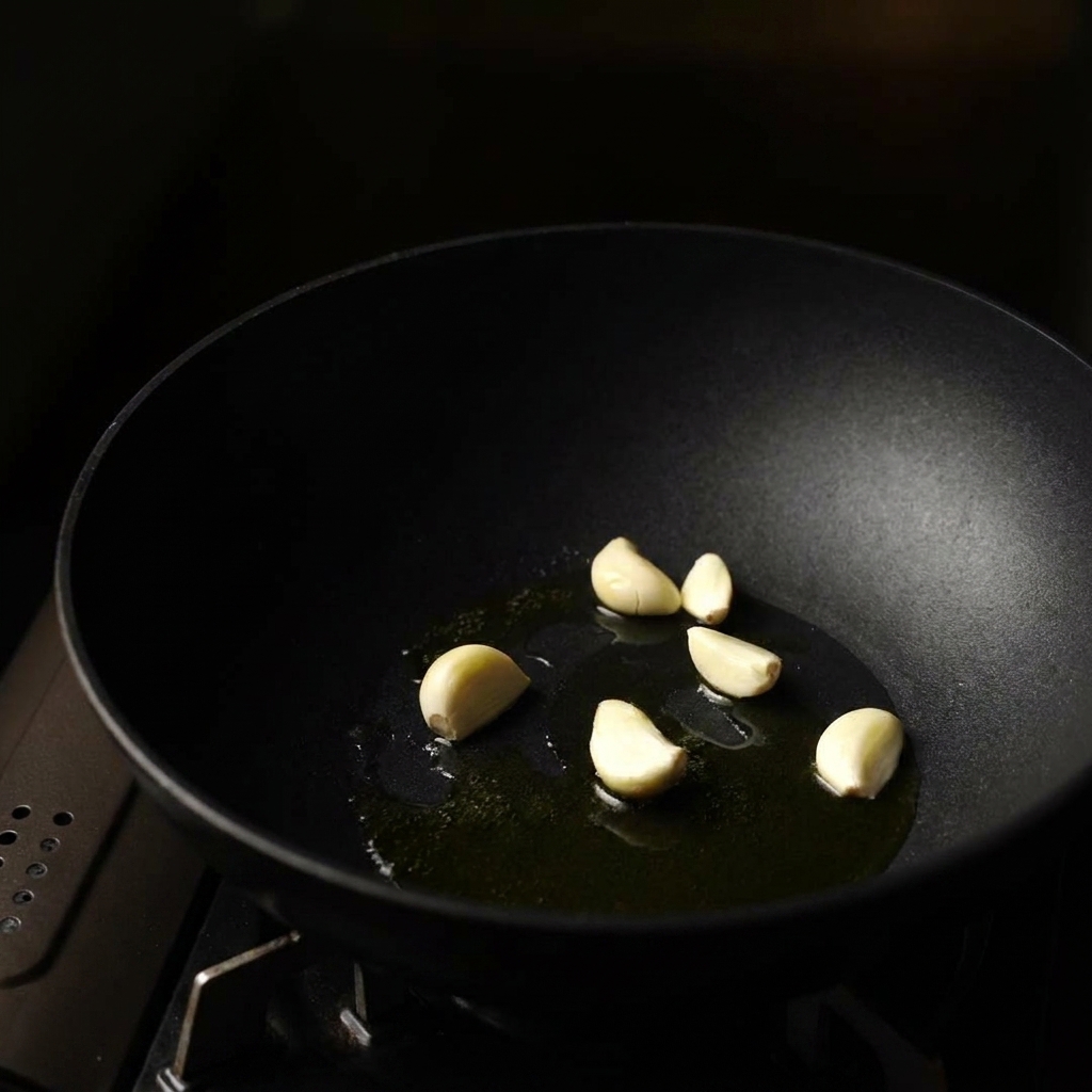 Knoblauch, Zwiebeln und Pilze werden in einer Pfanne angebraten.