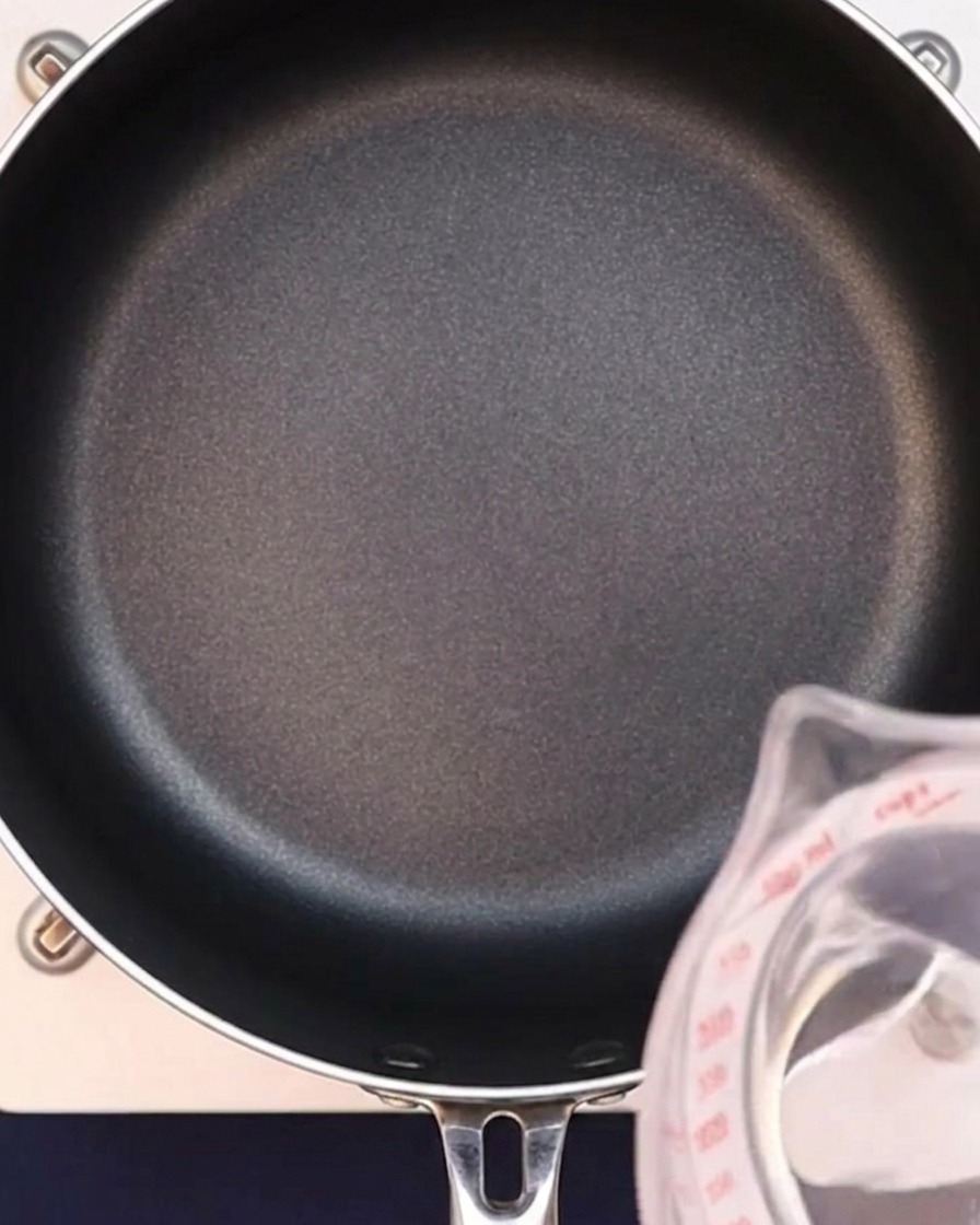 Wasser wird in eine schwarze Pfanne gegossen, um die Currybrühe zu beginnen.