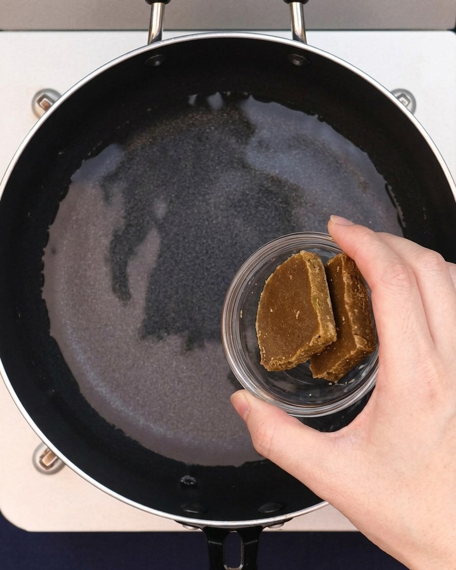 Zwei Curry-Würfel werden dem Wasser in der Pfanne hinzugefügt.