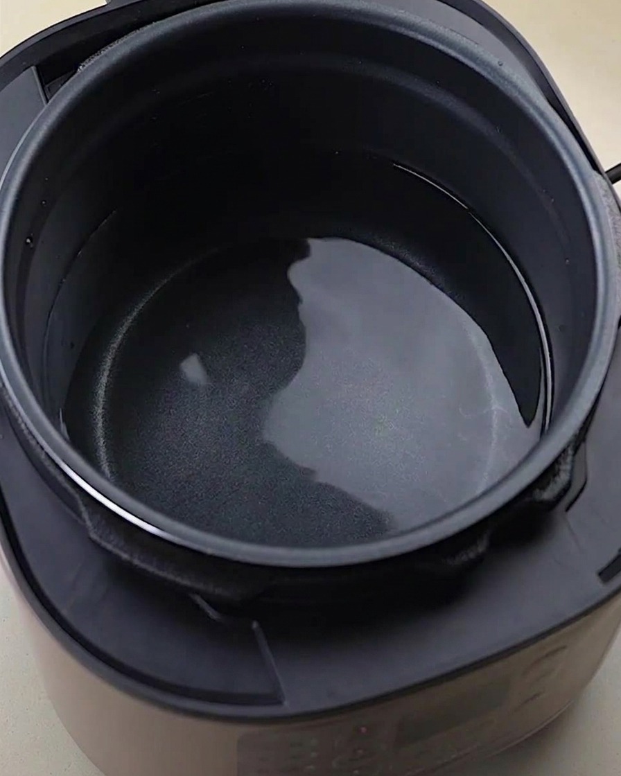 Rohe Hühnerknochen, Flügel und Füße in einem Schnellkochtopf mit Wasser