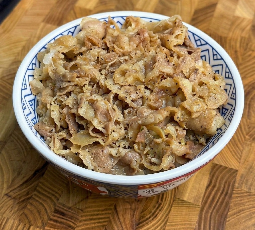 Eine großzügige Portion gebratenes Rindfleisch mit Frühlingszwiebeln auf lockerem weißen Reis in einer gemusterten Keramikschale.