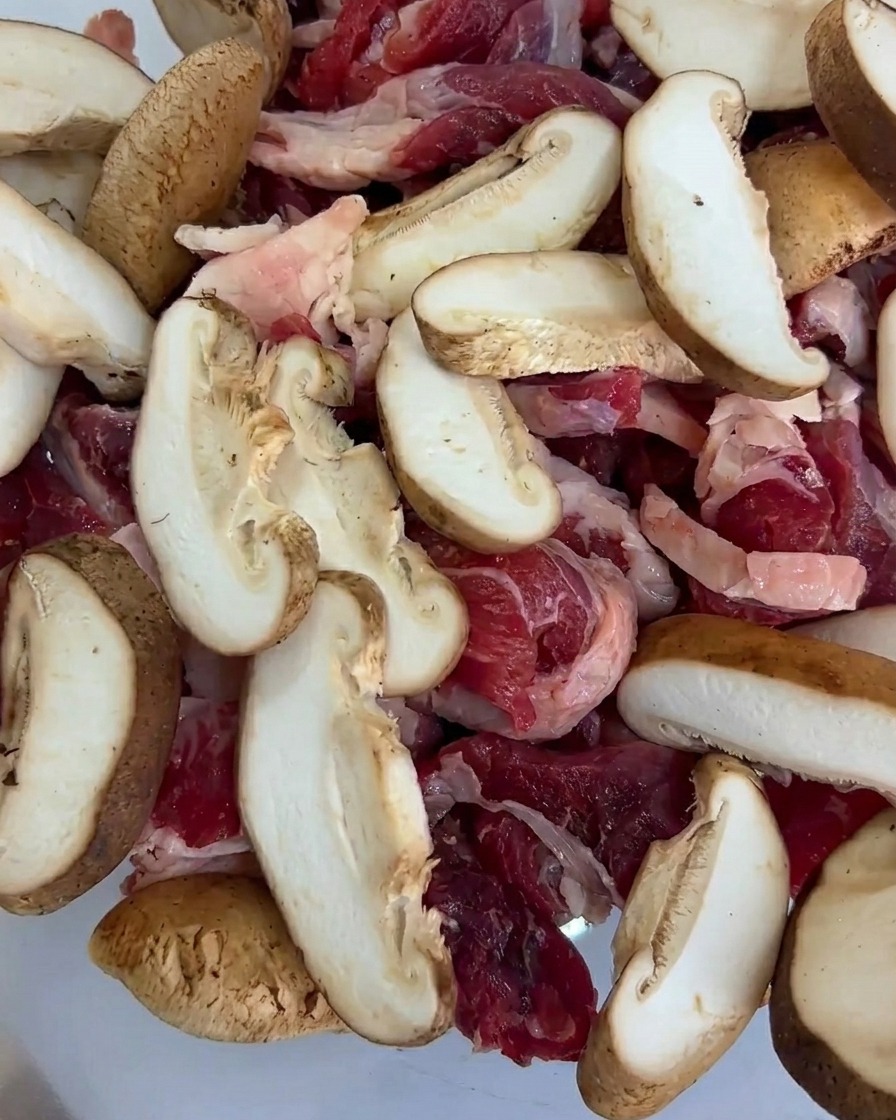 Stücke von Babymais in einer Schale mit Fleisch und Pilzen.