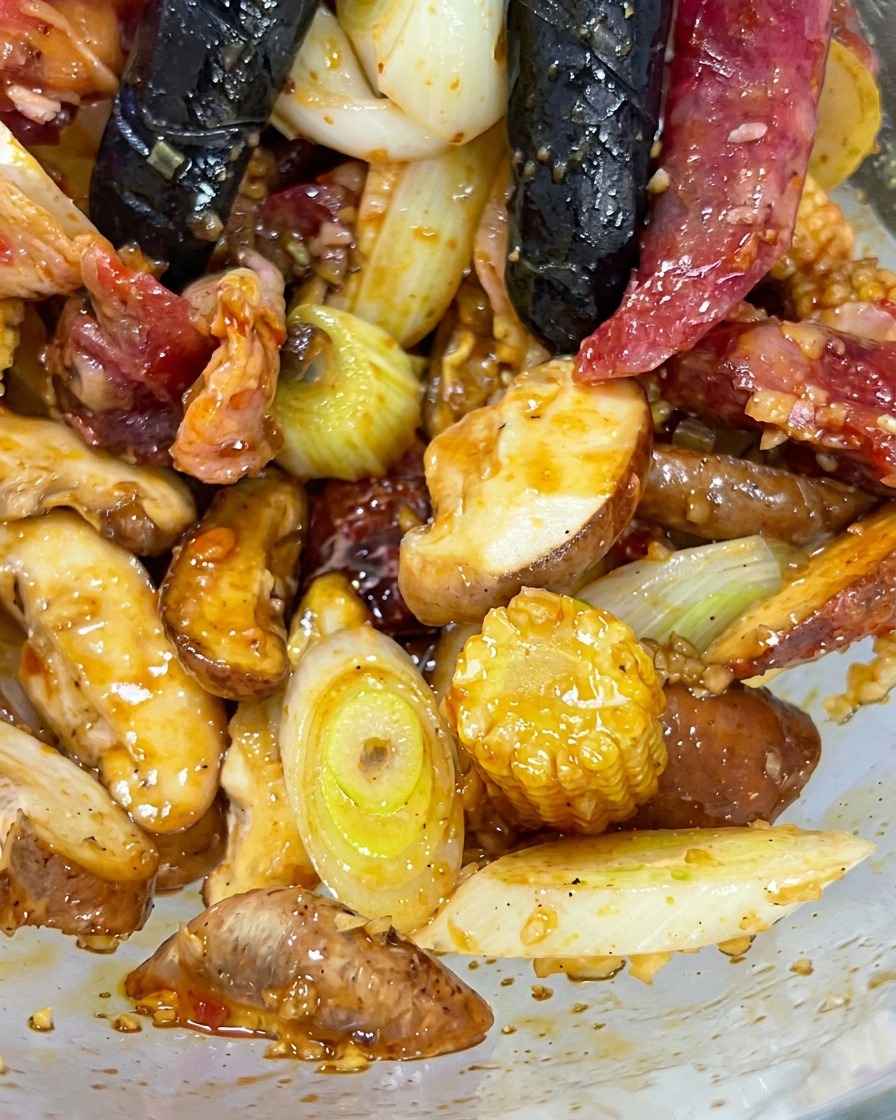 Hände vermengen Fleisch, Pilze und Gemüse in einer Schüssel.