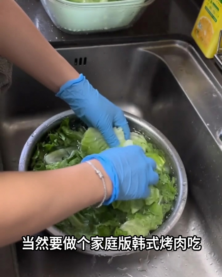 Frische grüne Salatblätter werden in einer großen Metallschüssel mit Wasser gewaschen.