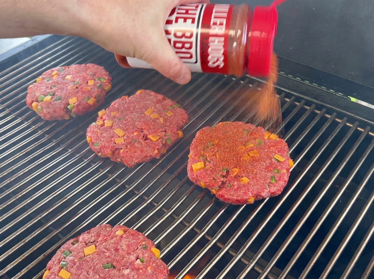 Mit BBQ-Rub gewürzte Rinder-Patties liegen auf dem Grillrost.