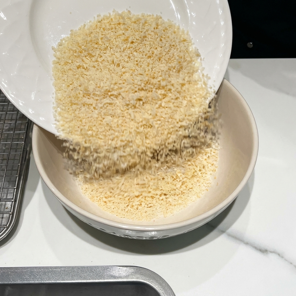 Eine Schüssel mit Semmelbröseln, Parmesan und Gewürzen, die vermischt werden.