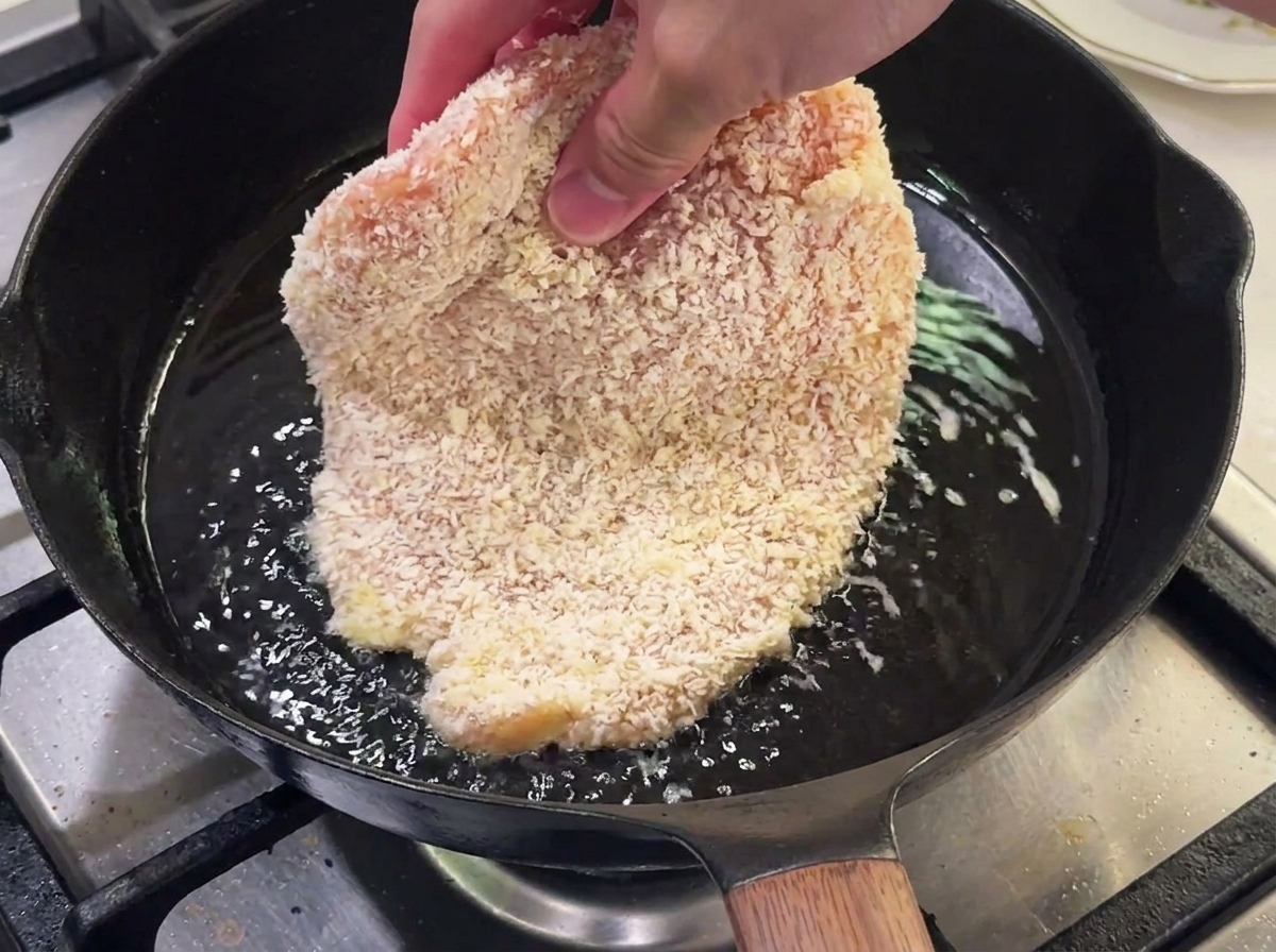 Paniertes Hähnchen brät in einer Pfanne mit heißem Öl.