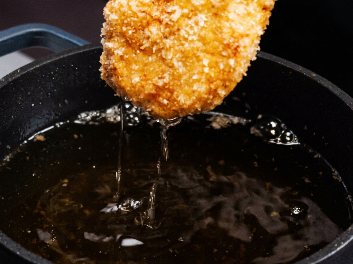 Goldbraun gebratenes Hähnchen wird aus der Pfanne genommen.