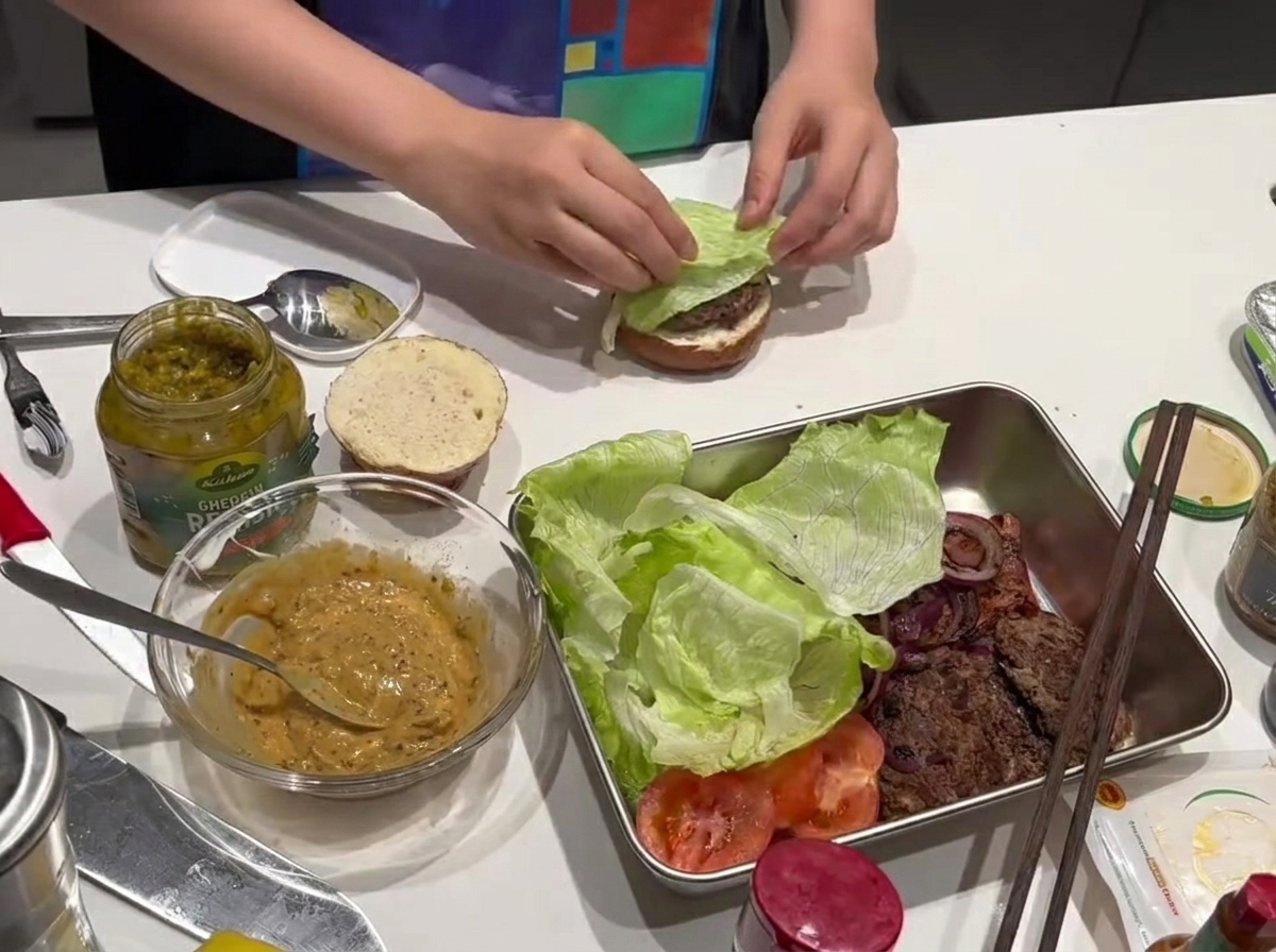 Ein frisches Salatblatt liegt auf dem gebratenen Fleisch-Patty.