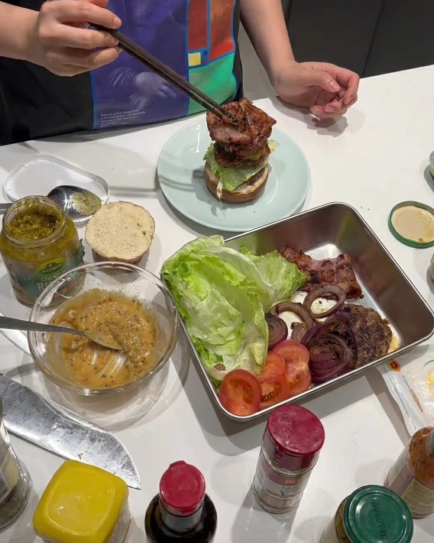 Knuspriger Speck wird auf den Burger gestapelt.