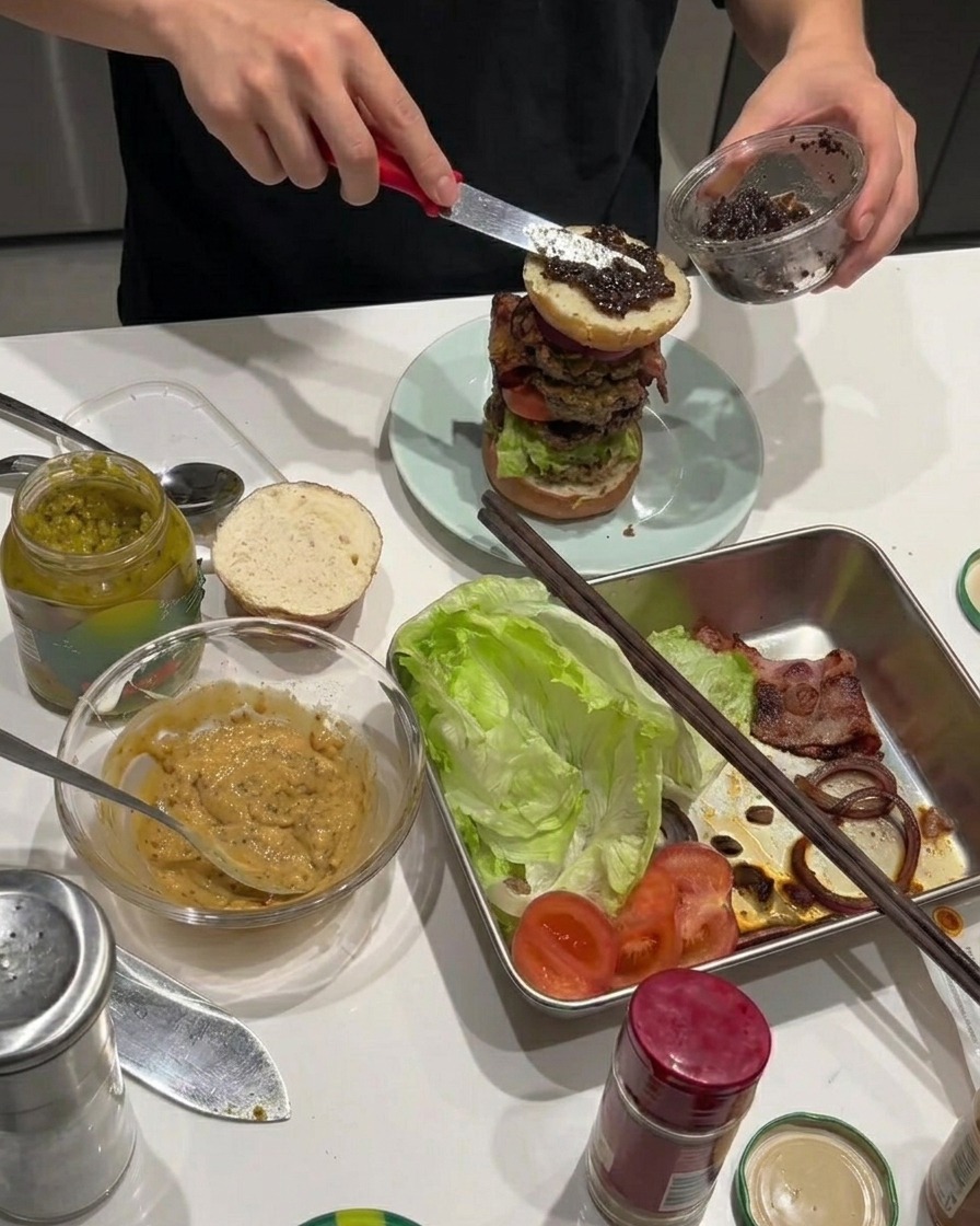 Trüffelpaste wird auf die gebratenen Zwiebelringe auf dem Burger gestrichen.