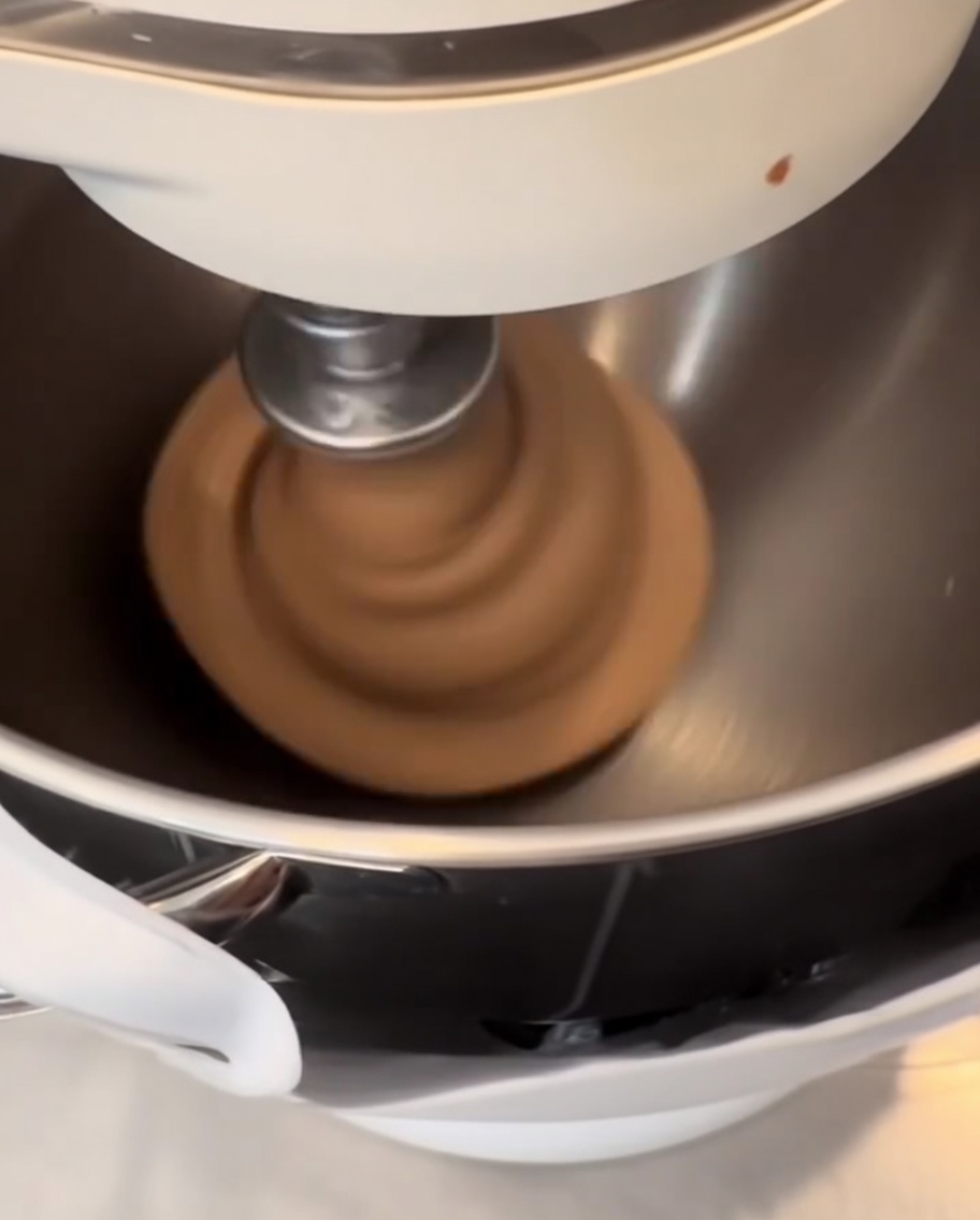 Dunkler, mit Kakao versetzter Teig wird auf einer Silikonmatte zu glatten, runden Kugeln geformt.