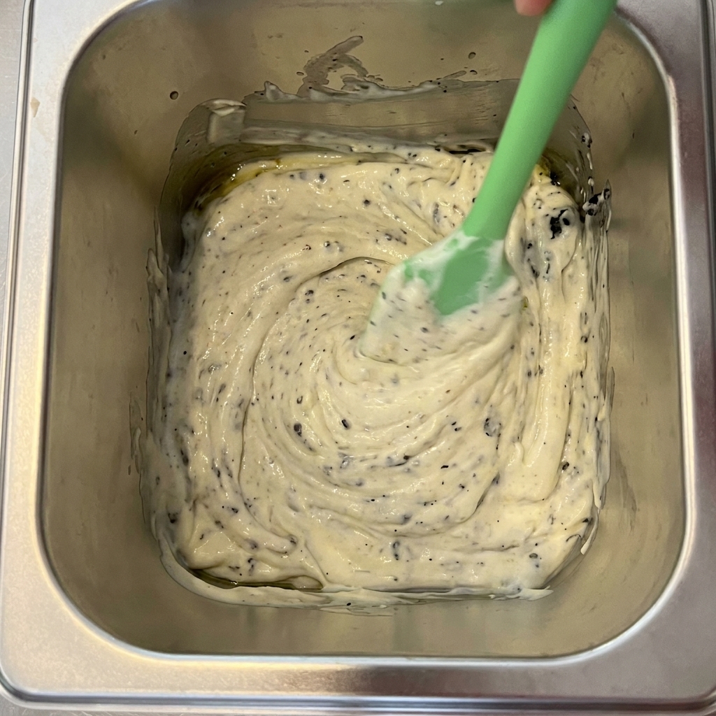 Schwarzer Trüffel, Mayonnaise und Olivenöl werden in einem Metallbehälter vermischt.