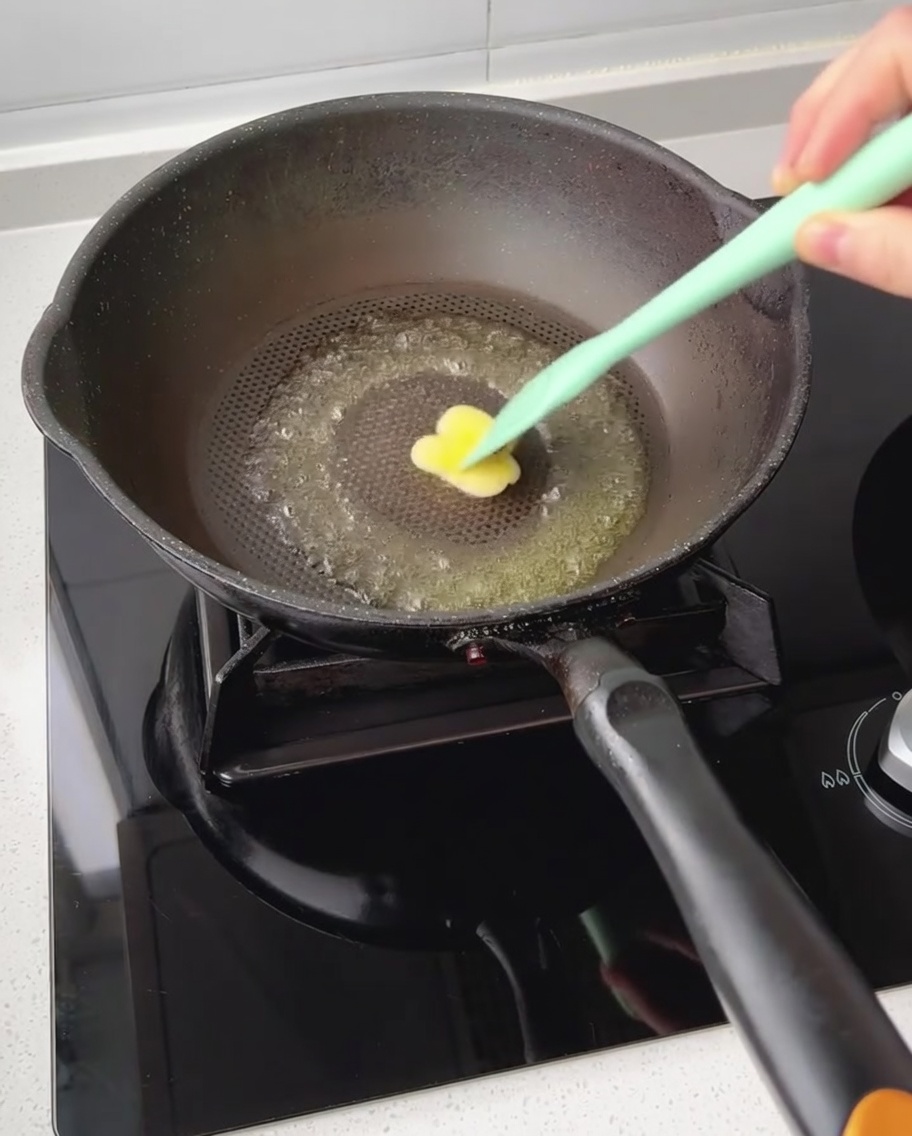 Ein Stück Butter schmilzt in einer beschichteten Pfanne und wird mit einem Spatel verteilt.