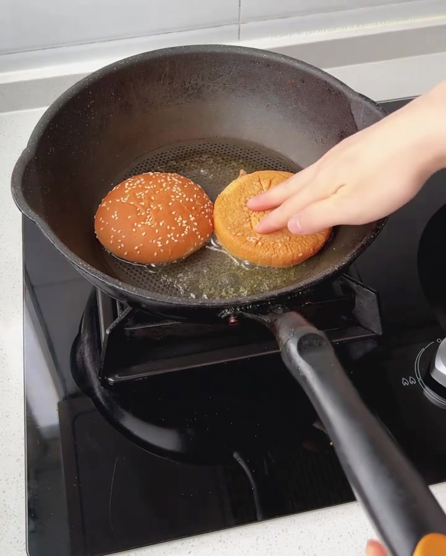 Burger-Bun-Hälften werden mit der Schnittfläche nach unten in der Butter geröstet.