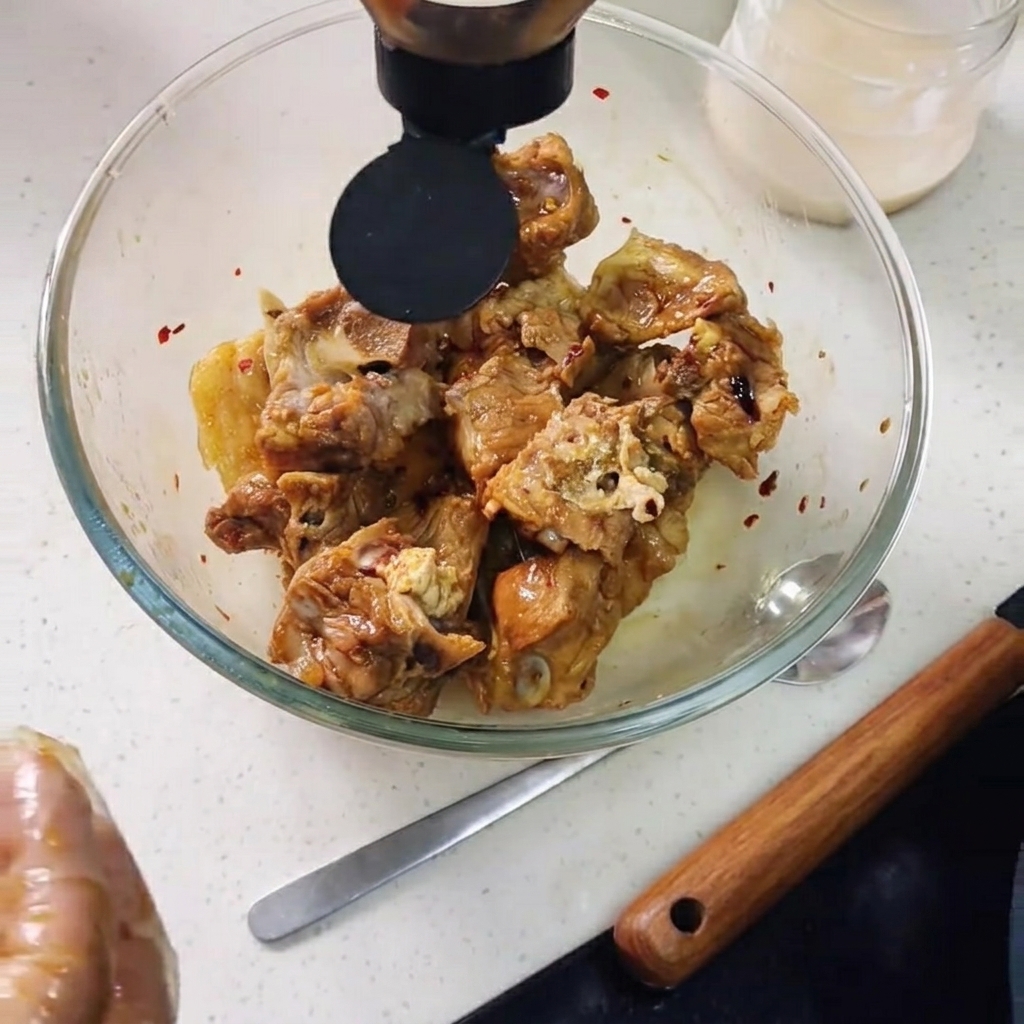 Austernsauce wird über die Schweinerippchen in die Schüssel gedrückt, dazu Zitronenscheiben.